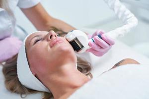 Adult woman in beauty salon undergoing face hydrogen purification photo