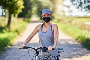 Young woman on a bike in countryside wearing a mask photo