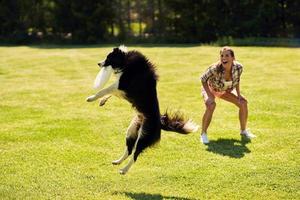 perro border collie y una mujer en un campo de agilidad foto