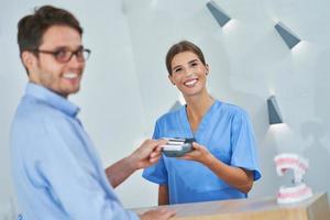 Patient paying for dental visit in clinic photo