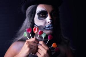 Spooky portrait of woman in halloween gotic makeup holding lillipops photo