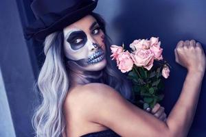 Spooky portrait of woman in halloween gotic makeup knocking on door photo