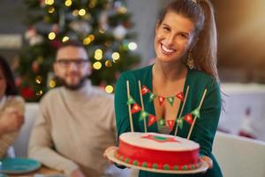 Group of friends celebrating Christmas at home with fancy cake photo