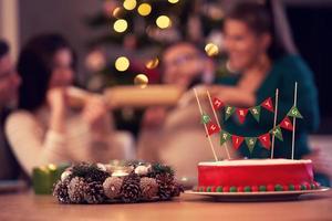 Group of friends celebrating Christmas at home with fancy cake photo