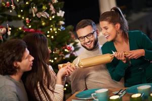 Group of friends celebrating Christmas by pulling crackers photo