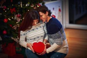 Adult couple with present over Christmas tree photo