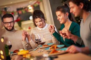 Group of friends praying over Christmas Thanksgiving table at home photo