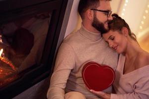 Adult couple with present over fireplace photo