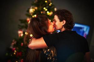Adult couple hugging over Christmas tree photo