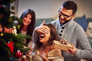 Adult couple with present over Christmas tree photo