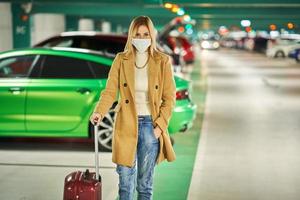 mujer adulta turista con máscara en el estacionamiento subterráneo del aeropuerto foto