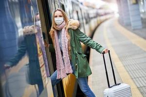 mujer adulta en la estación de tren con máscaras debido a las restricciones de covid-19 foto