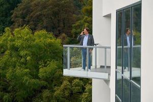 Businessman standing on balcony against nature photo