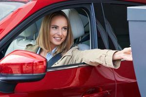 Woman getting ticket from parking meter in underground parking photo