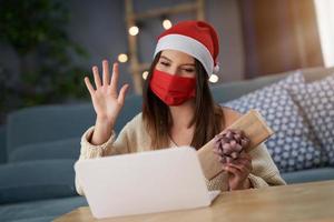 Adult woman celebrating Christmas at home and making video call with friends photo