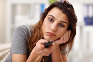 Beautiful young woman relaxing at home watching tv photo