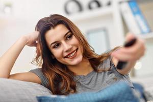 Beautiful young woman relaxing at home watching tv photo