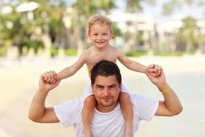 padre divirtiéndose en la playa con su pequeño hijo foto