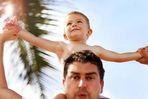 Father having fun on the beach with his little son photo