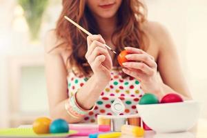 Attractive woman painting Easter eggs at home photo