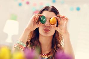 mujer atractiva pintando huevos de pascua en casa foto