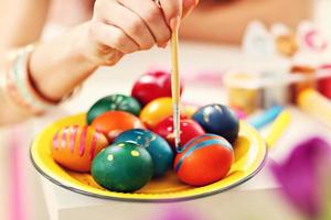 Attractive woman painting Easter eggs at home photo