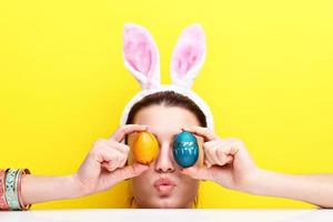 mujer joven feliz con orejas de conejo y huevos de Pascua foto