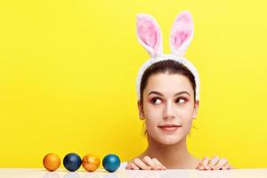 mujer joven feliz con orejas de conejo y huevos de Pascua foto