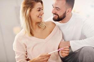 Happy couple with pregnancy test in bedroom photo