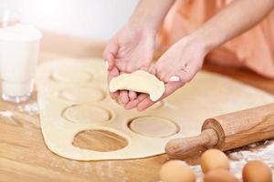 Young woman trying to make pierogi in kitchen photo