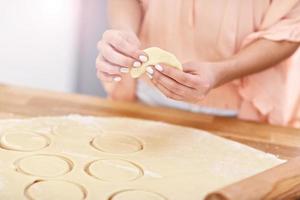 Young woman trying to make pierogi in kitchen photo