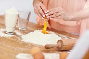 Young woman trying to make pierogi in kitchen photo