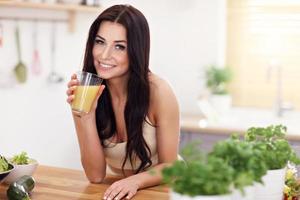 Fit smiling young woman with healthy juice in modern kitchen photo