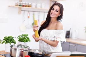 Young woman trying to prepare pasta in kitchen photo