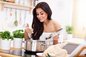 Young woman trying to prepare chicken soup in kitchen photo