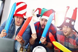 Happy male friends cheering and watching sports on tv photo