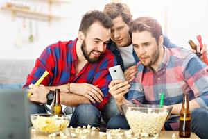 Happy male friends cheering and watching sports on tv photo