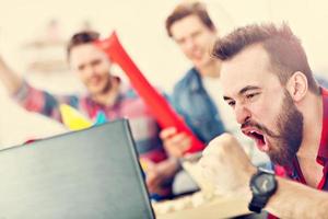 Happy male friends cheering and watching sports on tv photo