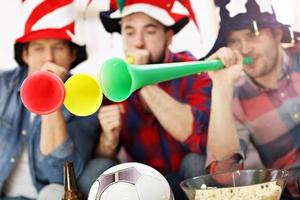 Happy male friends cheering and watching sports on tv photo