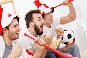 amigos varones felices animando y viendo deportes en la televisión foto