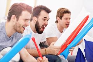 Happy male friends cheering and watching sports on tv photo