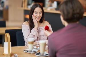 Young man proposing to his girlfriend in a cafe photo