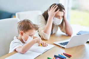 Boy and exhausted mother trying to work at home during coronavirus pandemic photo