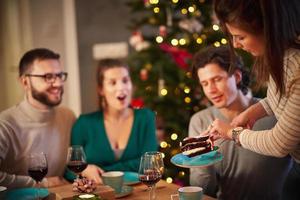 Group of friends celebrating Christmas at home with fancy cake photo