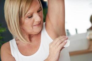 Senior woman using deo roll-on in the bathroom photo