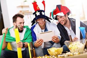 Happy male friends cheering and watching sports on tv photo