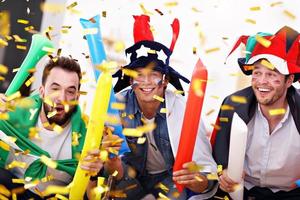 Happy male friends cheering and watching sports on tv photo