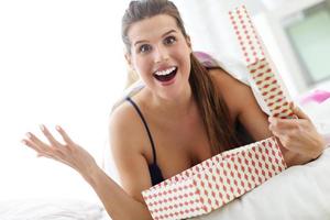 Young woman unpacking a surprise present in bed photo