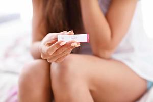 Young woman with pregnancy test in bed photo