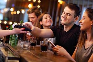 Group Of Friends Paying For Meal In Restaurant photo